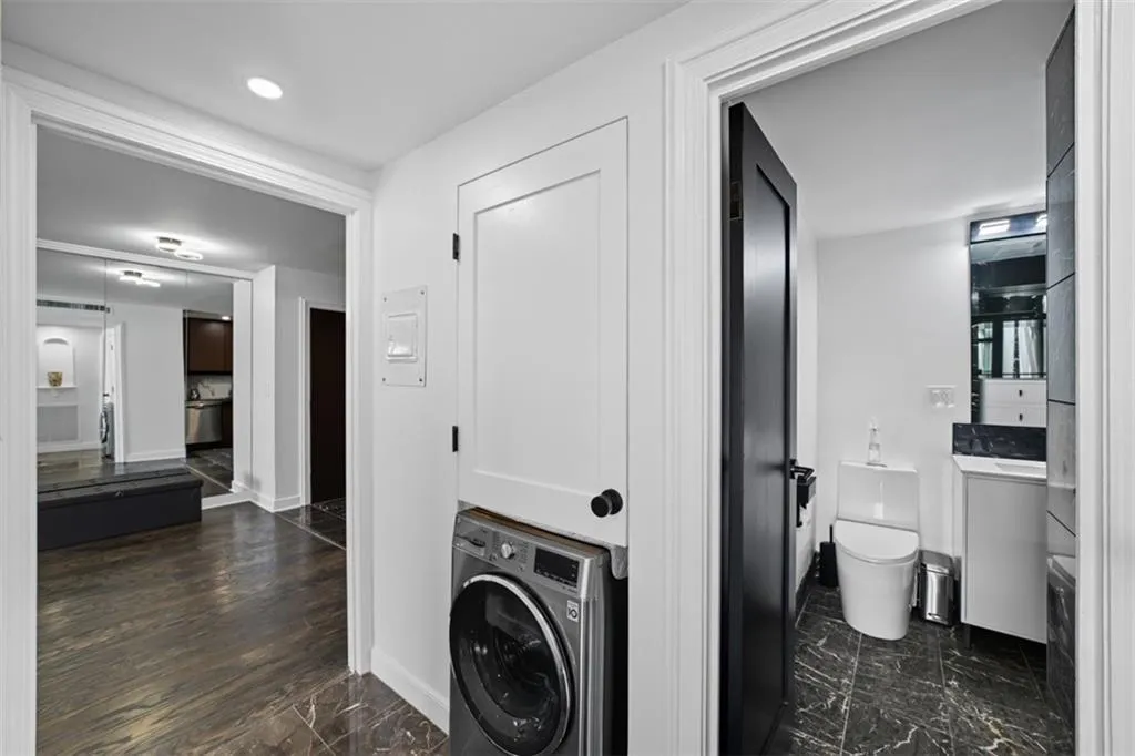 Laundry room featuring washer / clothes dryer and dark marble finish flooring