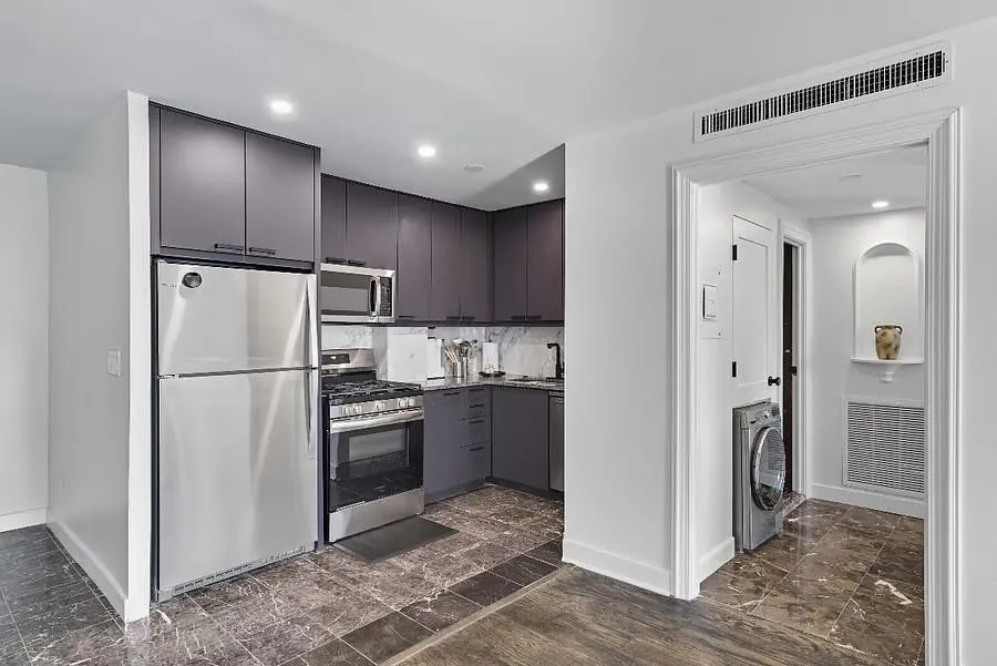 Kitchen with appliances with stainless steel finishes, washer / dryer, modern cabinets, dark marble finish floors, and recessed lighting