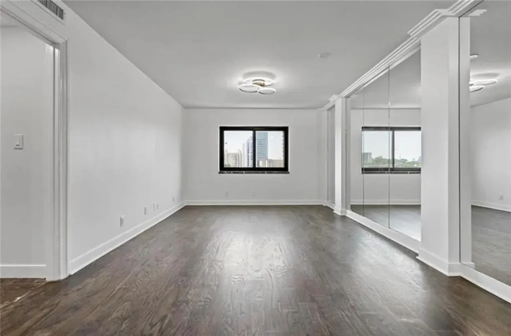 Empty room featuring dark wood-style floors and plenty of natural light