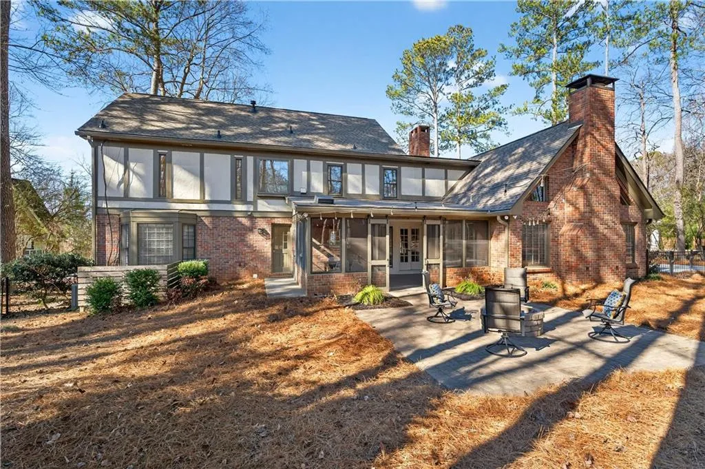 Back of house with a sunroom, brick siding, a chimney, and a shingled roof
