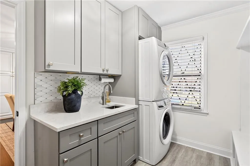 Laundry area with stacked washer / drying machine and mudroom cabinets off kitchen