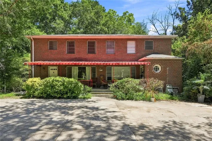 Brick exterior featuring a full-width covered porch with red awnings