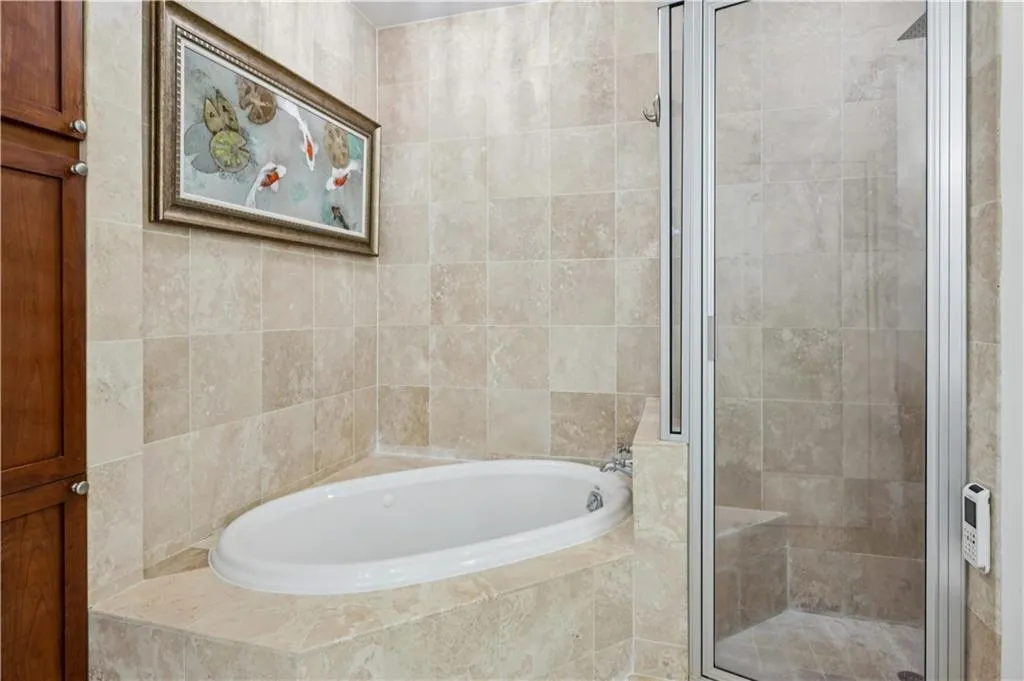 Full bathroom with a garden tub, a stall shower, and tile walls