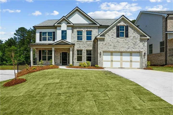 Two-story residence featuring brick and siding facade, covered front porch, and an attached two-car garage