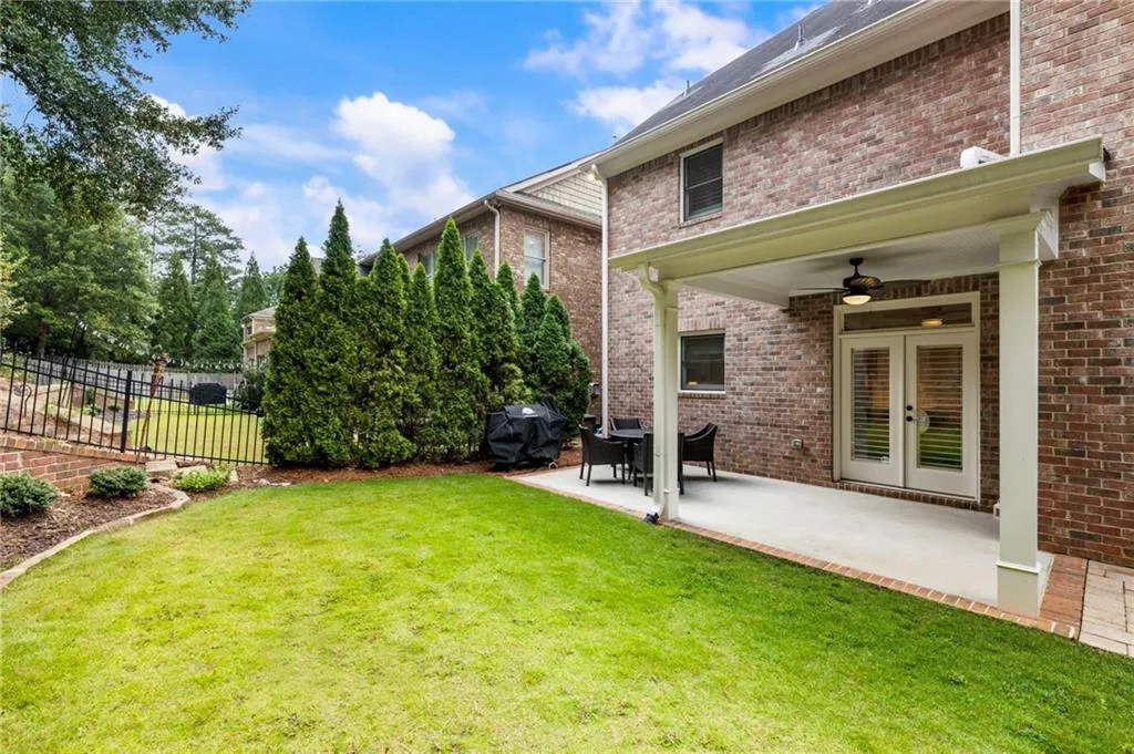 View of yard featuring a ceiling fan, a patio area, and french doors