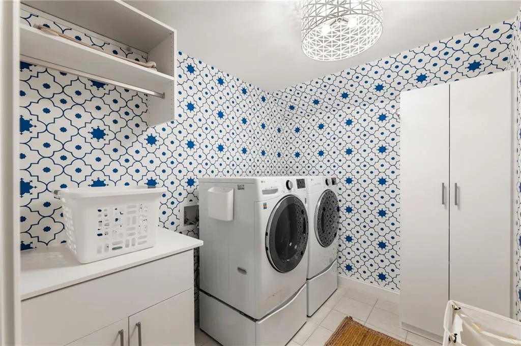Laundry area featuring light tile patterned floors, cabinet space, and washer and clothes dryer