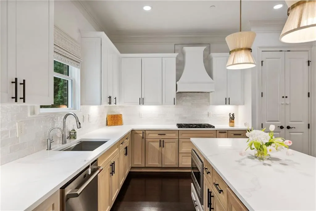 Kitchen with tasteful backsplash, pendant lighting, light brown cabinetry, appliances with stainless steel finishes, and light stone countertops