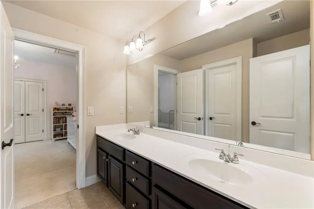 Full bath with double vanity and light tile patterned floors
