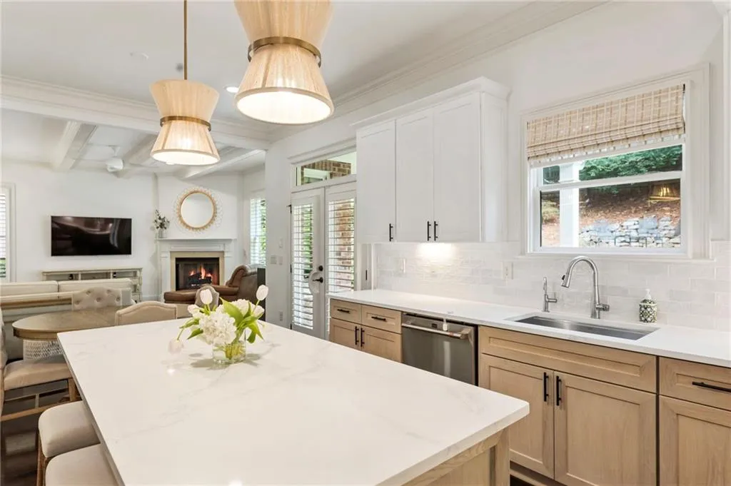 Kitchen featuring open floor plan, a lit fireplace, beam ceiling, pendant lighting, and backsplash