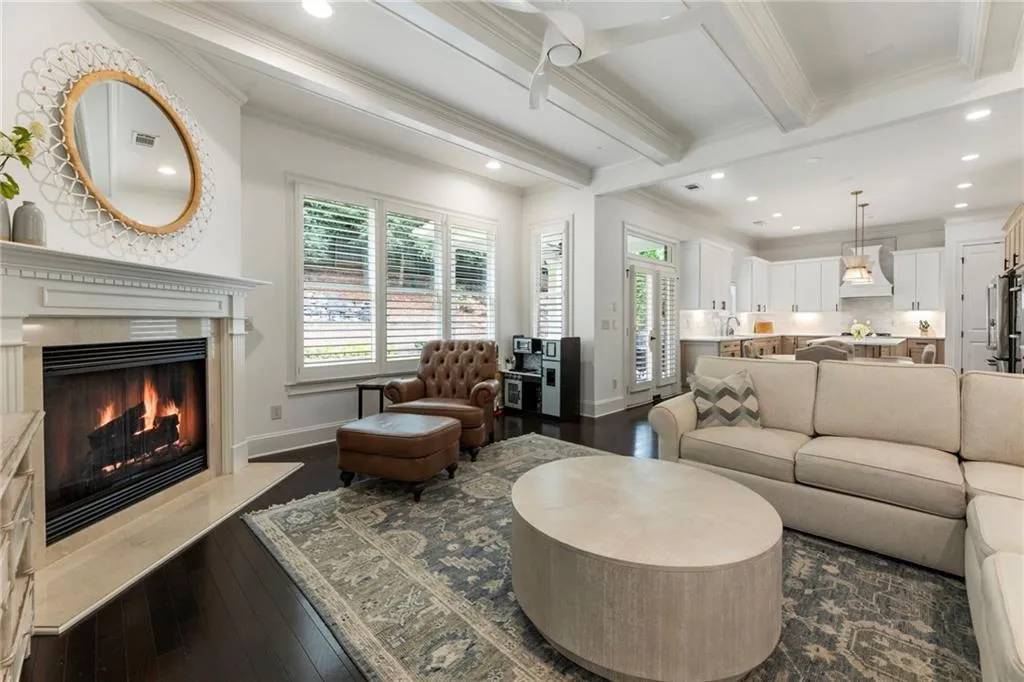 Living room with dark wood-style floors, recessed lighting, beamed ceiling, ornamental molding, and a premium fireplace