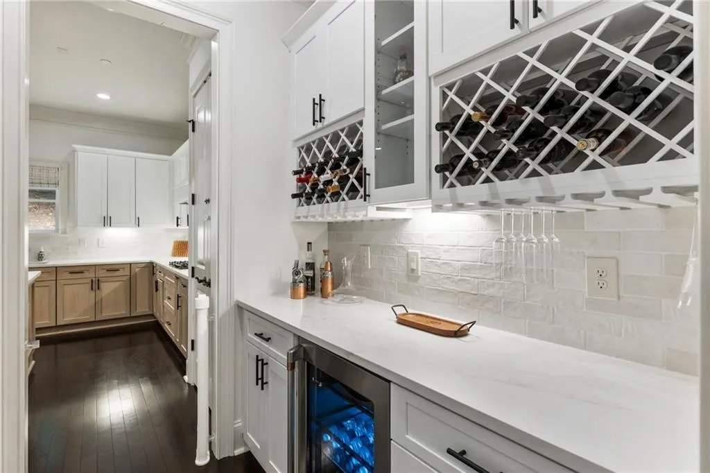 Bar with backsplash, beverage cooler, white cabinets, and glass insert cabinets