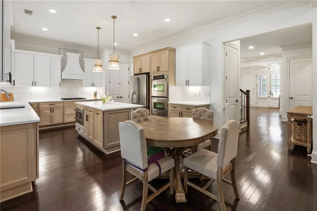 Kitchen featuring light brown cabinetry, a center island, decorative backsplash, crown molding, and decorative light fixtures