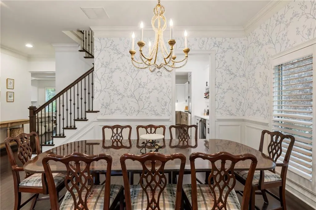 Dining space with a decorative wall, wallpapered walls, crown molding, a wainscoted wall, and stairs