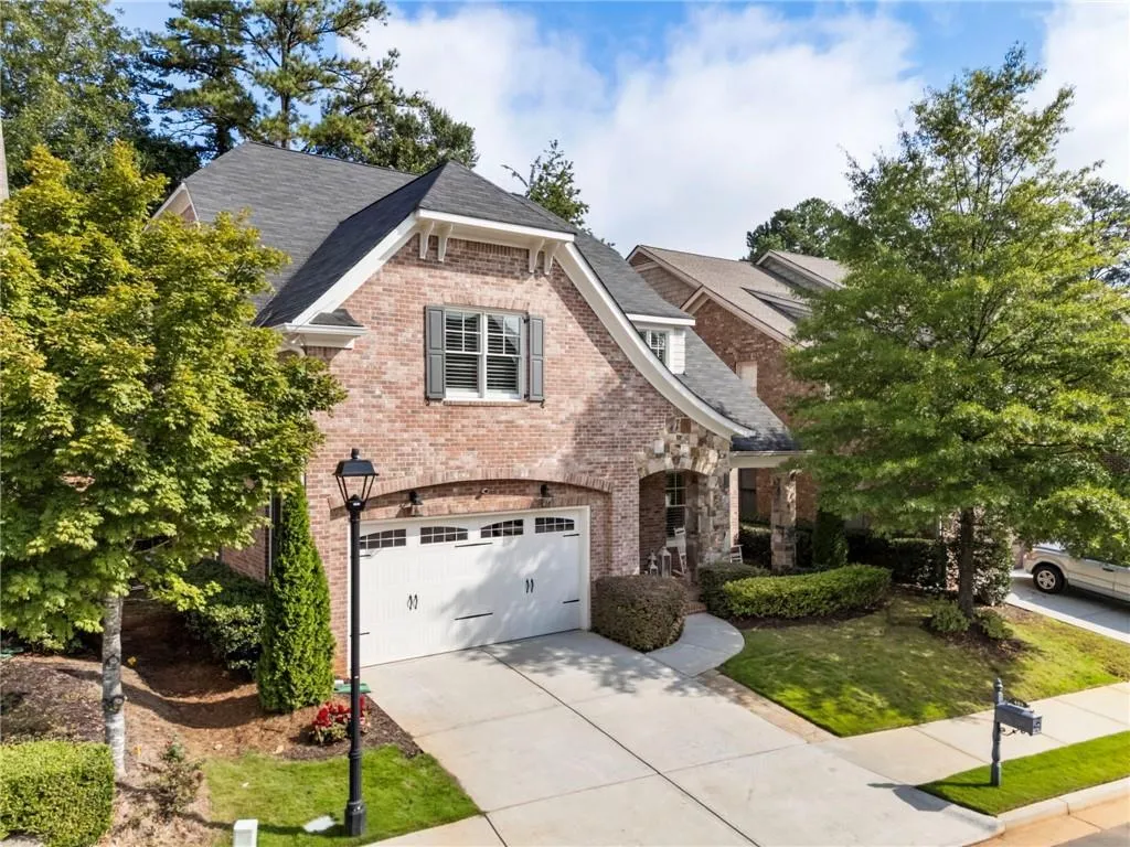 View of front of property with brick siding, concrete driveway, roof with shingles, an attached garage, and a front yard