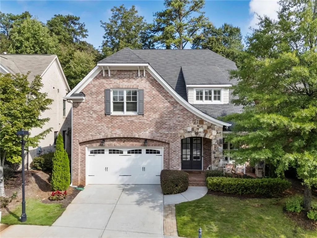 View of front facade featuring concrete driveway, brick siding, an attached garage, roof with shingles, and a front yard