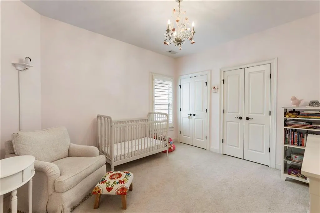 Bedroom featuring carpet flooring, two closets, a crib, and a chandelier