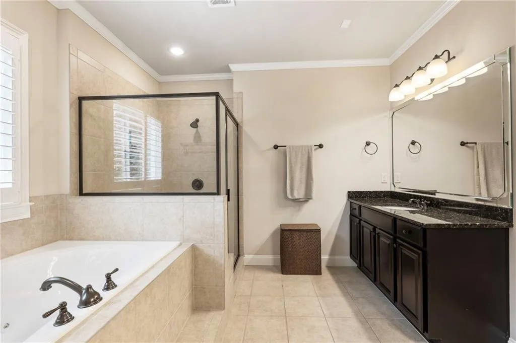 Full bathroom with a garden tub, light tile patterned flooring, vanity, a shower stall, and ornamental molding