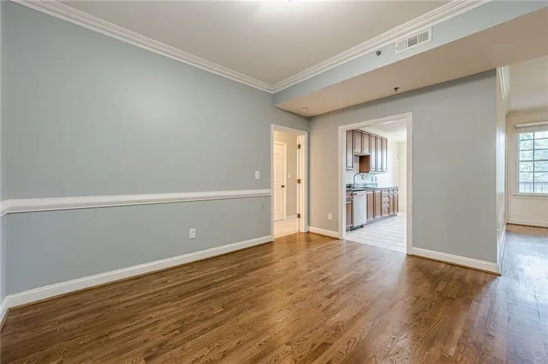 Empty room featuring ornamental molding, wood finished floors, and healthy amount of natural light