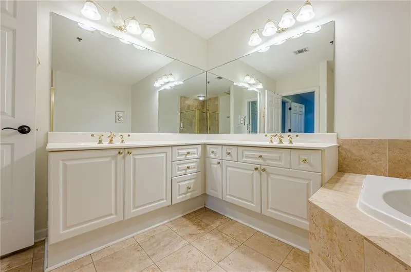 Full bathroom with double vanity, light tile patterned floors, a garden tub, and a shower stall