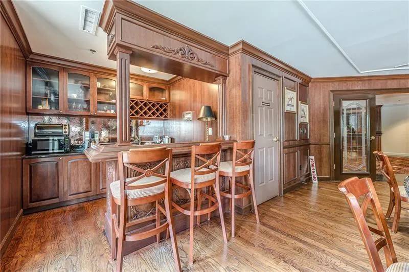 Kitchen with wood walls, glass insert cabinets, ornamental molding, dark countertops, and light wood finished floors