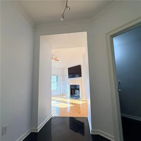 Glossy black tile flooring, track lighting, crown molding, wood-finish flooring, built-in shelving