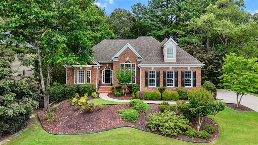View of front of property featuring a front lawn, brick siding, and roof with shingles