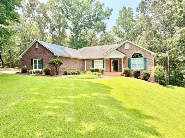 Brick exterior featuring a covered entry, arched window, and green window shutters