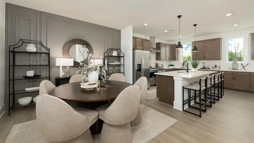 Open concept layout with wood-finish flooring, a kitchen island with seating, pendant lighting, and stainless steel appliances