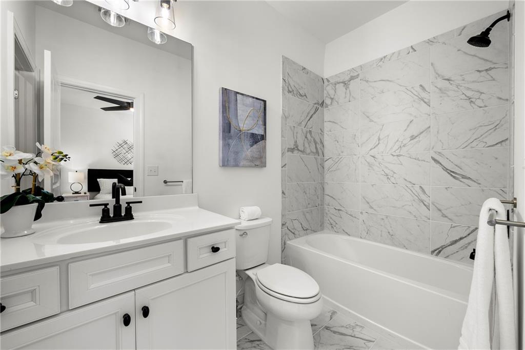 Full bathroom for 2nd bedroom featuring vanity, ceiling fan, tiled shower / bath combo.