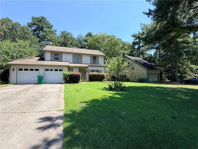 Two-story residence with a dual two-car garage, concrete driveway, and a spacious front lawn
