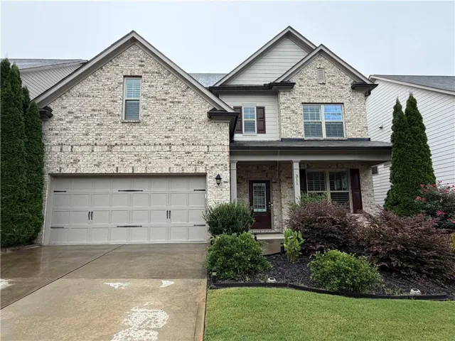 Brick and siding exterior, two-car garage, covered entry, landscaped front yard, and exterior lighting