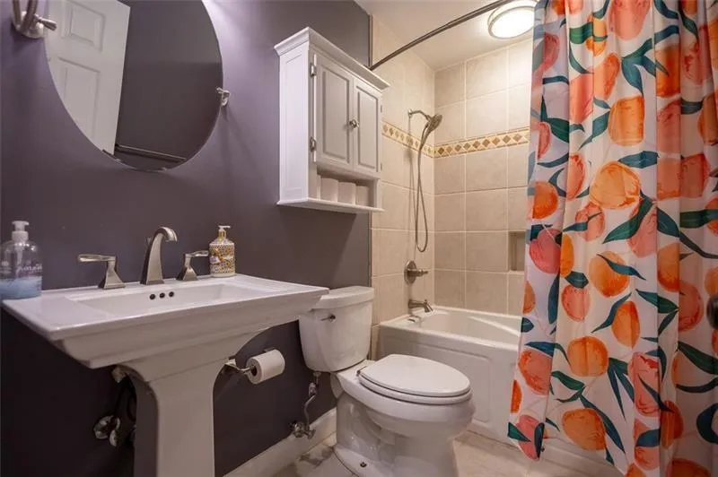 Bathroom featuring tile patterned floors, shower / tub combo with curtain, and toilet
