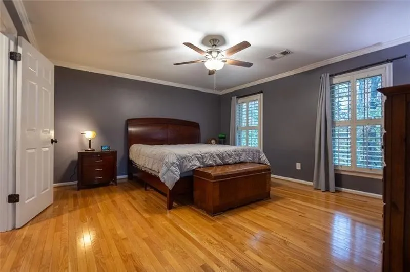 Bedroom with multiple windows, light hardwood / wood-style flooring, ceiling fan, and ornamental molding
