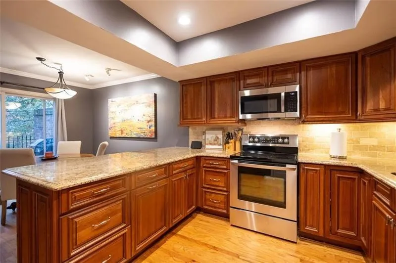 Kitchen with light stone countertops, kitchen peninsula, and appliances with stainless steel finishes