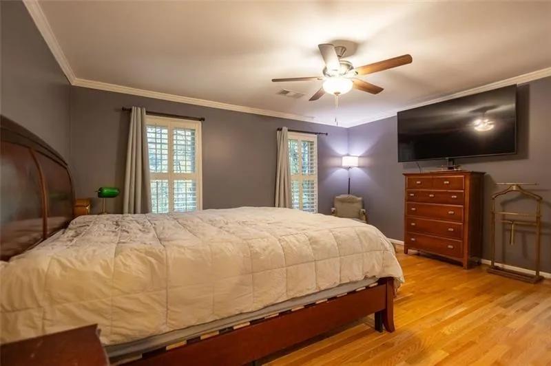 Bedroom featuring light hardwood / wood-style flooring, ceiling fan, and crown molding