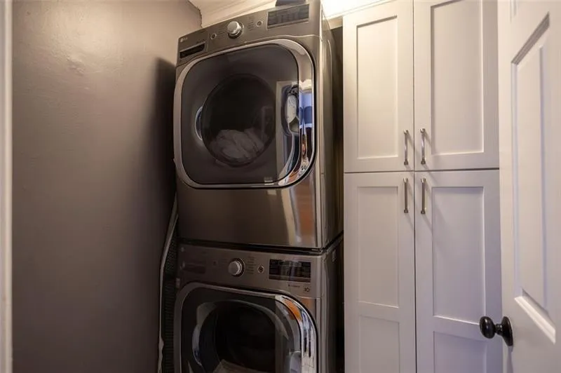 Laundry room featuring cabinets and stacked washing maching and dryer