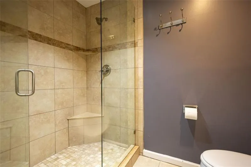Bathroom with toilet, tile patterned flooring, and walk in shower