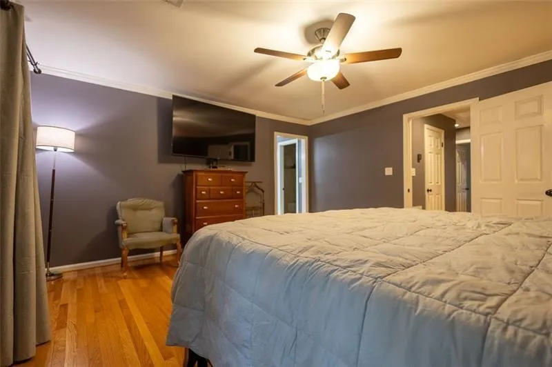 Bedroom featuring ceiling fan, crown molding, and light hardwood / wood-style floors