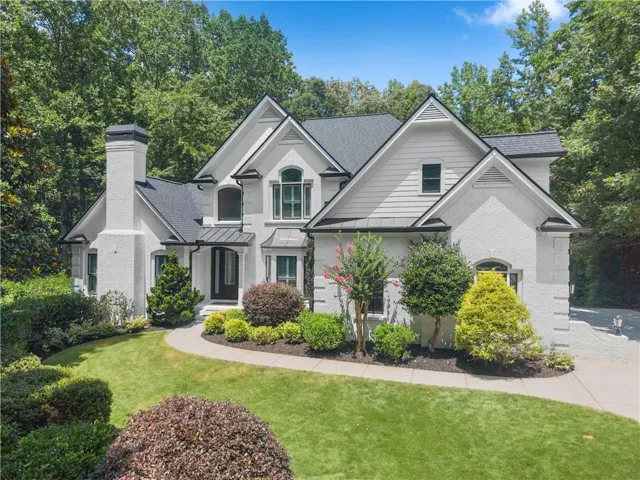 Stately white brick and siding exterior with dark shingle roofing