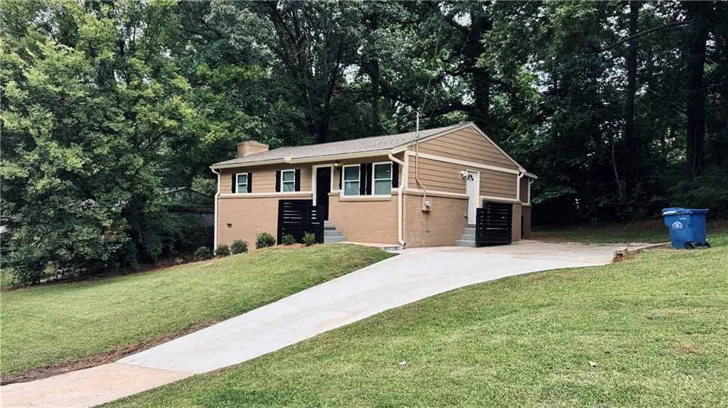 View of front facade with brick siding, a chimney, a front yard, driveway, and a garage