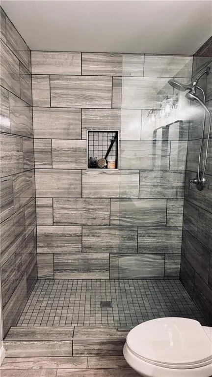 Full bathroom featuring a stall shower and toilet