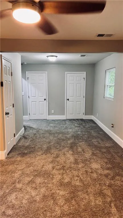 Unfurnished bedroom with dark carpet and baseboards