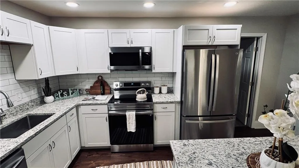 Kitchen with stainless steel appliances, light stone countertops, decorative backsplash, and recessed lighting