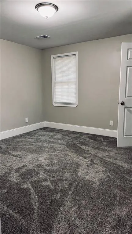Unfurnished room with dark carpet and baseboards