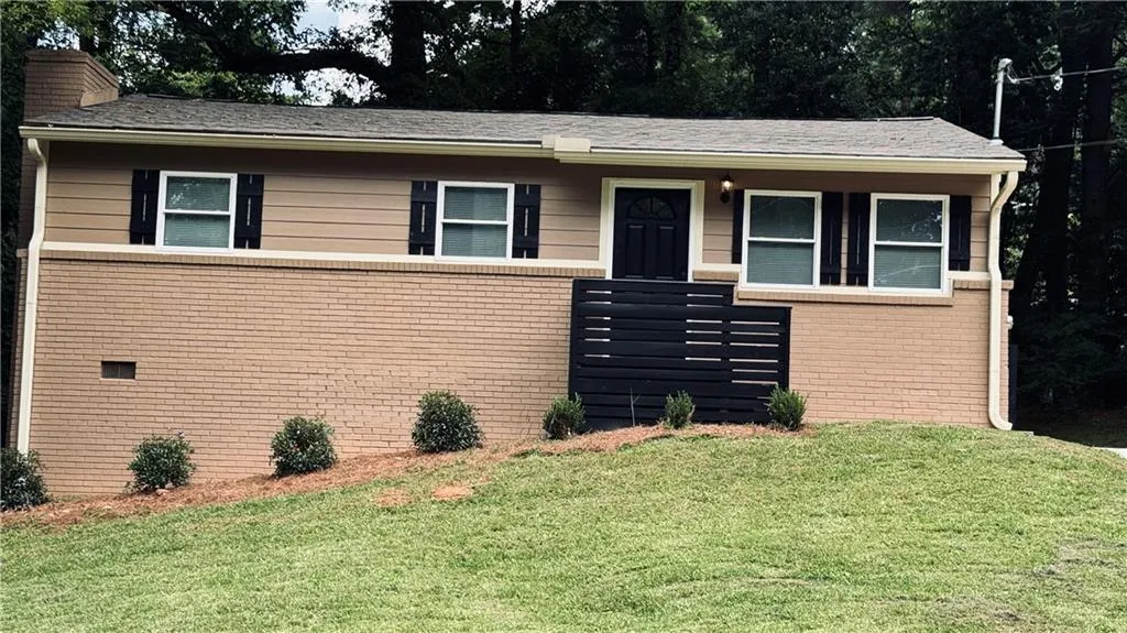 Ranch-style house featuring a front lawn, a chimney, and brick siding