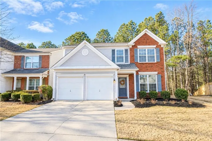 Brick and siding exterior with blue window shutters, attached two-car garage, concrete driveway, and front landscaping