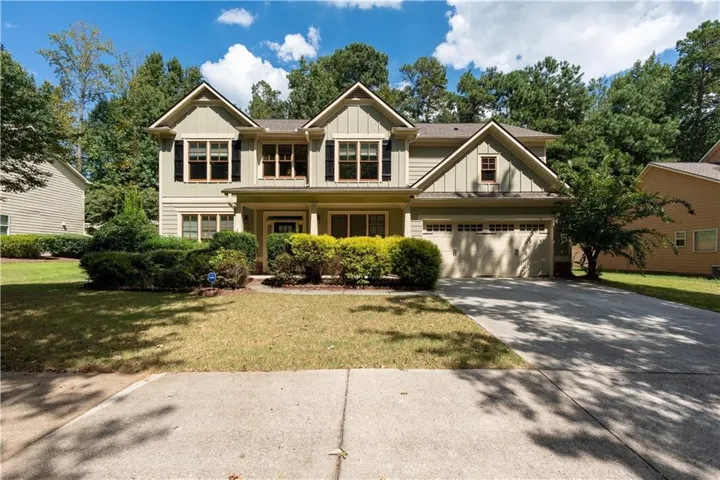 Two-story residence with a light green exterior, multiple gables, and a two-car garage
