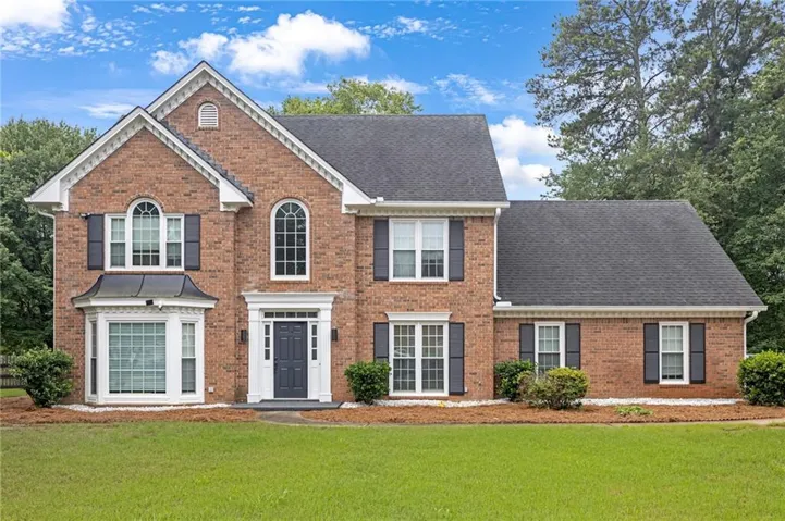 Brick exterior featuring a gabled roofline, dark shutters, and a prominent bay window with a copper-colored accent roof
