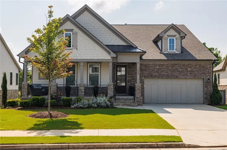 Stone and shingle facade featuring a covered front porch with stone columns and wrought iron railing