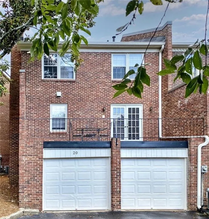Rear view of property with brick siding, asphalt driveway, and a garage